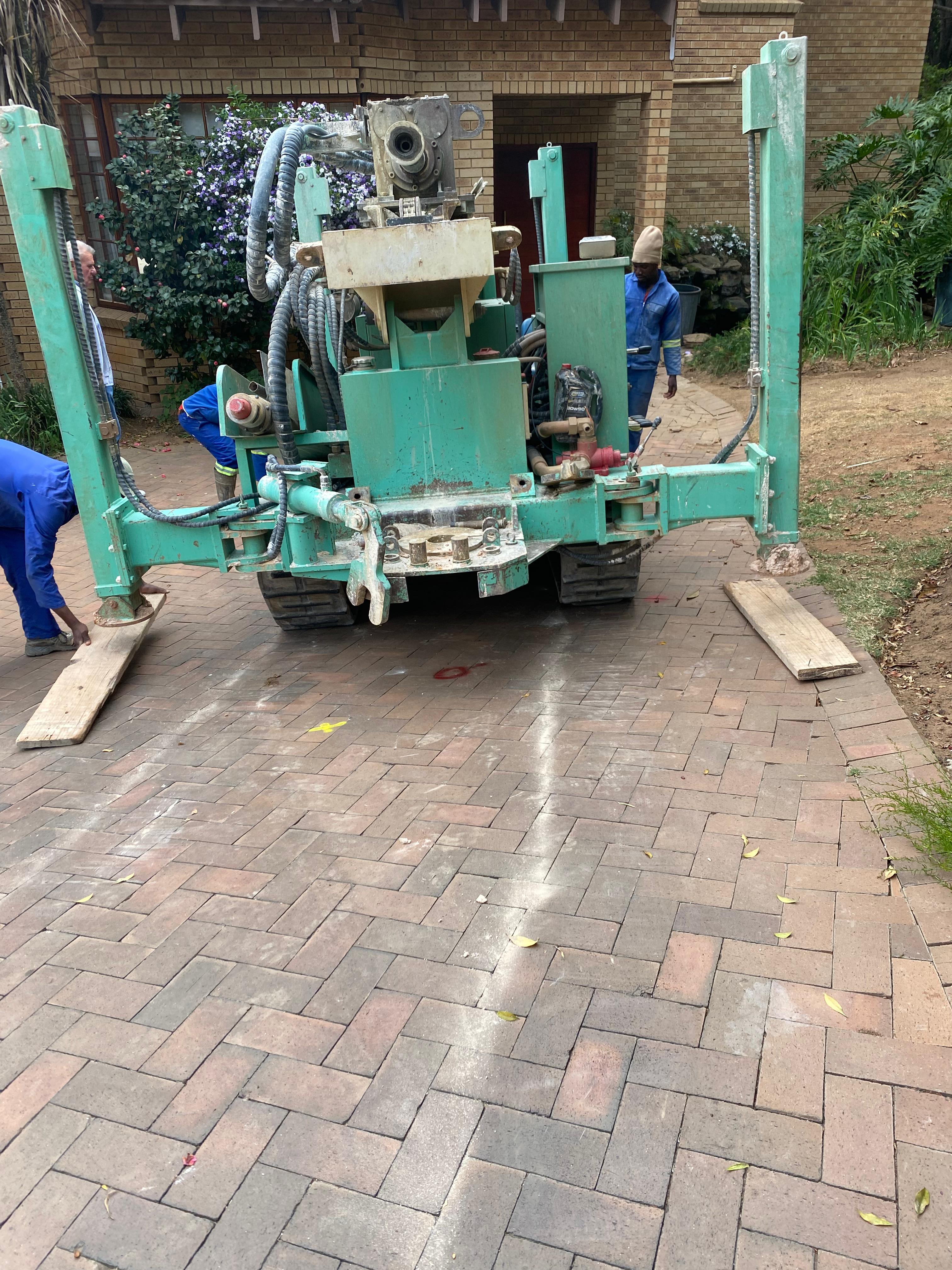 Crawler drilling rig parked on residential brick driveway